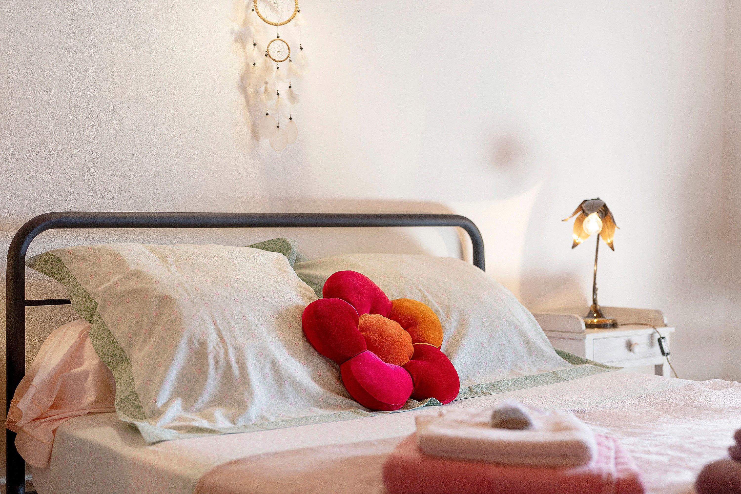 Un lit bien fait, avec une literie à motifs, un coussin décoratif et une lampe de chevet.