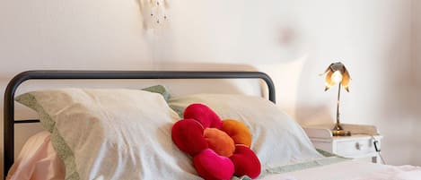 A neatly made bed with patterned bedding, a decorative pillow, and a bedside lamp.