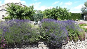 A stone building with a garden of lavender and other plants.