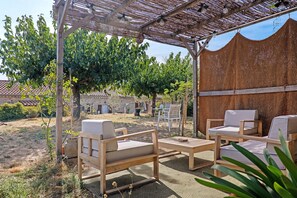 An outdoor seating area with wooden furniture and a woven shade structure. - Guest Room “L’Adrienne” with Shared Garden and Wi-Fi (Chazeaux)