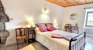 Un dormitorio con cama, dos mesitas de noche, una silla, cómoda y espejo.
