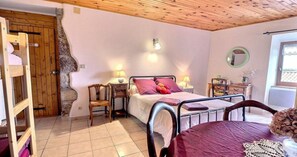 A bedroom with a bed, bedside tables, a chair, a wooden door, and a window.