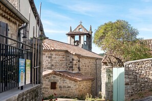 Un bâtiment en pierre doté d’un clocher, d’une porte en métal et d’un arbre.