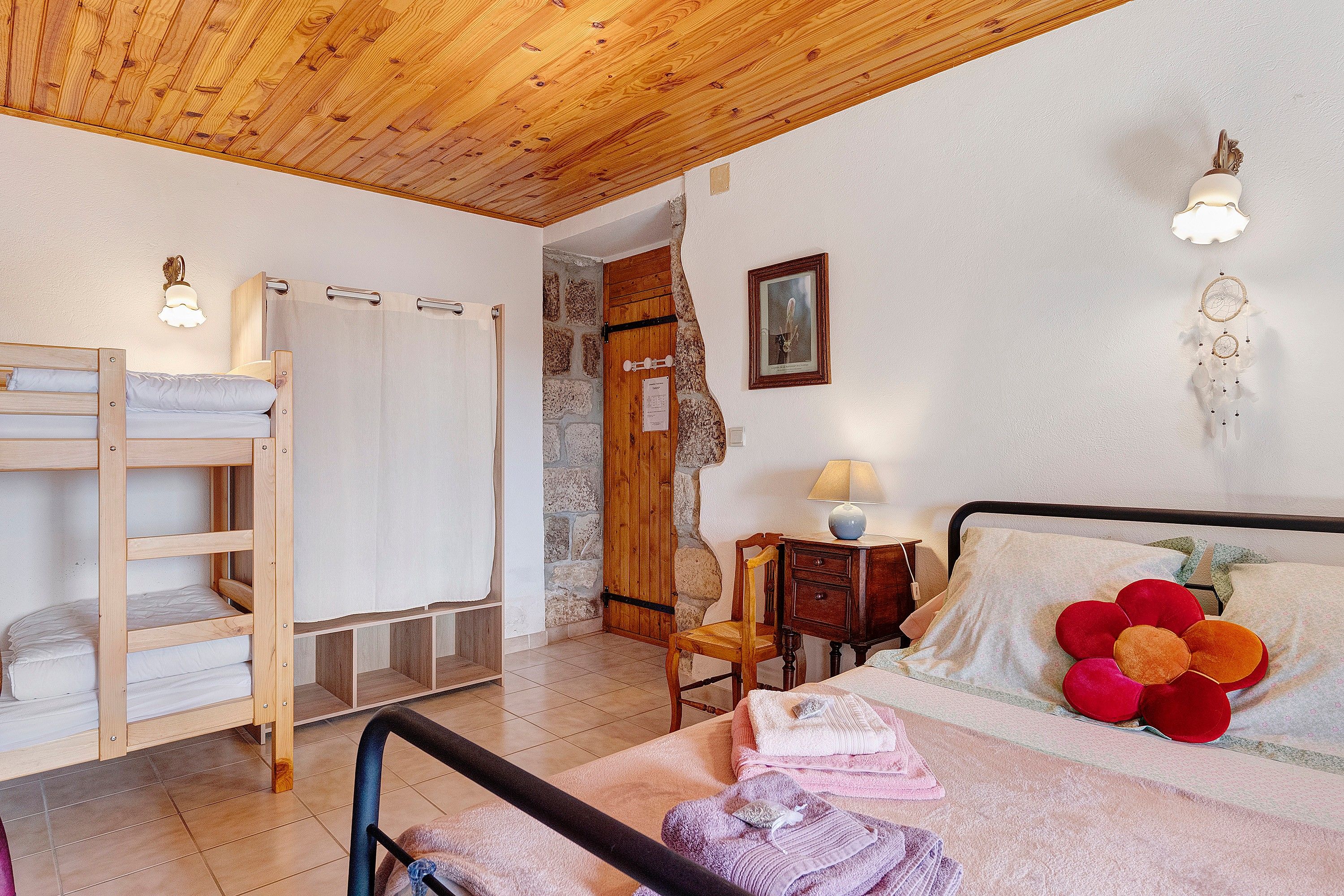 Une chambre avec un lit superposé, une table de chevet avec une lampe, une chaise et un luminaire fixé au mur.