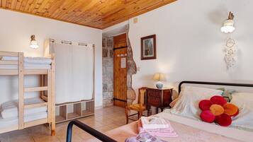 A bedroom with a bunk bed, a bedside table with a lamp, a chair, and a wall-mounted light fixture.
