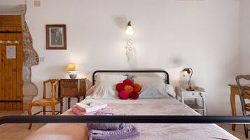 Une chambre à coucher comprenant un lit, une table de chevet, une lampe, une chaise et un attrape-rêves fixé au mur.
