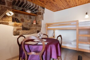A room with a bunk bed, a stone wall, a table with a purple tablecloth, and a chair. - Guest Room “L’Adrienne” with Shared Garden and Wi-Fi (Chazeaux)