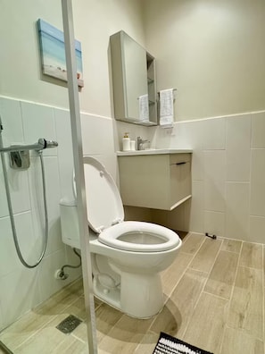 Ein Badezimmer mit Toilette, Dusche, Waschbecken und Spiegel.