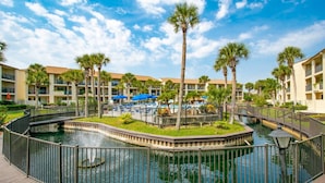 Ein Resort mit einem zentralen Wasserspielplatz, Palmen und einem Poolbereich.