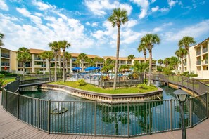 Ein Resort mit einem zentralen Wasserspielplatz, Palmen und einem Poolbereich.