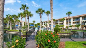 Ein Resort mit Poolbereich, Palmen und einem Gebäude mit Balkonen.