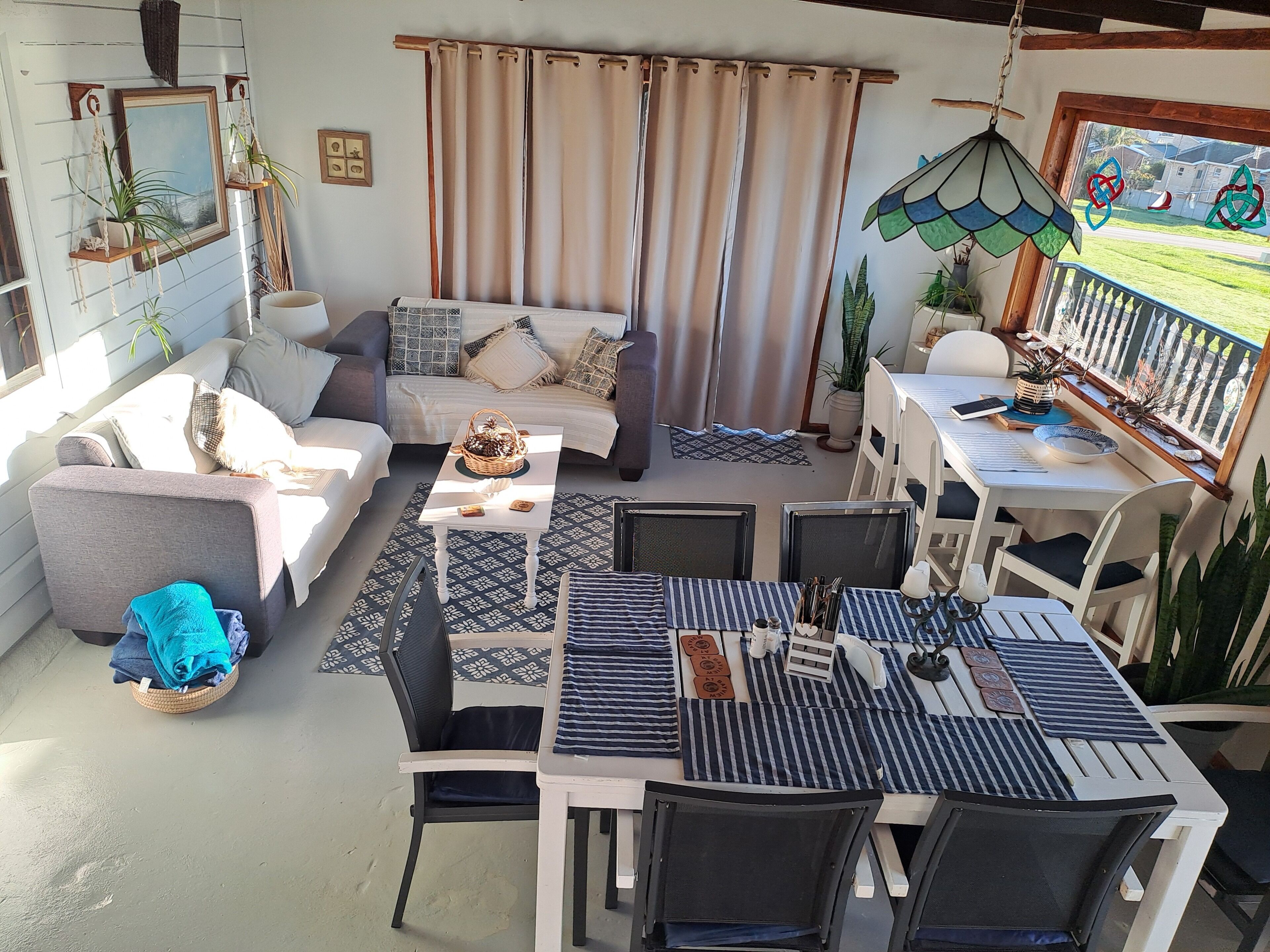 Un salon confortable avec un canapé, une table à manger, des chaises et un balcon agrémenté de plantes.