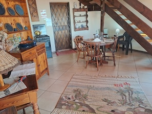 Une cuisine rustique avec des meubles en bois, un poêle et un coin repas comprenant une table ronde et des chaises.