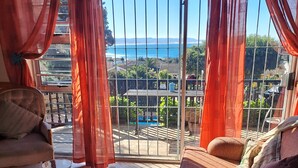 A living room with a sofa, a coffee table, and a view of a balcony with a pool. - BayView Guest House  (Jeffreys Bay)