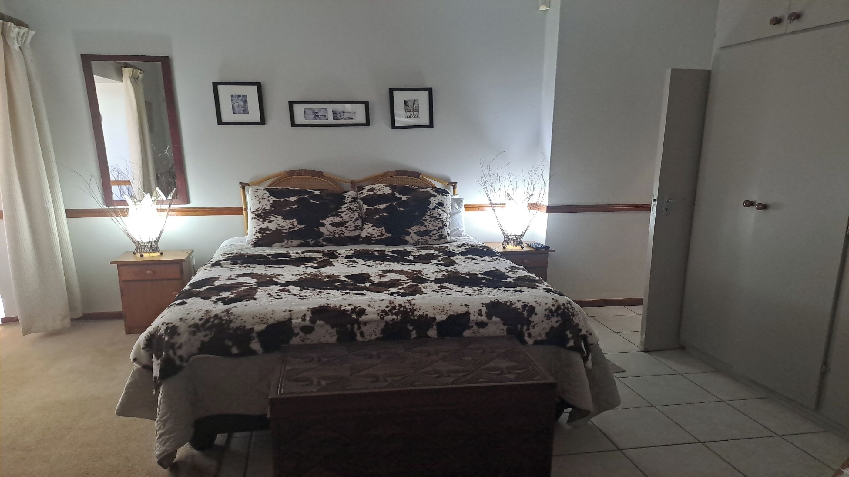 A bedroom with a bed, bedside tables, a wardrobe, and framed pictures on the wall.