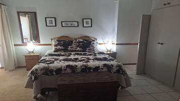 A bedroom with a bed, bedside tables, a wardrobe, and framed pictures on the wall.