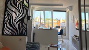 A modern interior with a bed, a dining area, and a view of the outdoors. - Naturist Village - Heliopolis AB - 30 m² - ocean view (Agde)