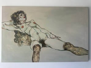 Ein Gemälde zeigt eine Person mit lockigem Haar und einem roten Fleck auf der Brust, die auf einer Fläche liegt.