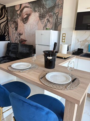 Eine moderne Küche mit Esstisch für zwei Personen, einem Kühlschrank und einer Mikrowelle.