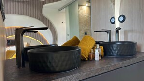 A modern bathroom with a curved design, a black sink, a mirror, and a towel. - The Bb Port Nature Coursives (Agde)
