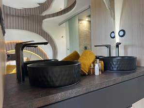 A modern bathroom with a curved design, a black sink, a mirror, and a towel. - The Bb Port Nature Coursives (Agde)