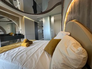 A modern hotel room with a large bed, a mirror, and a bathroom visible through a glass partition. - The Bb Port Nature Coursives (Agde)