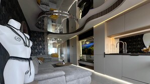 A modern living room with a grey sectional sofa, a round coffee table, and a white mannequin with jewelry. - The Bb Port Nature Coursives (Agde)