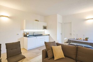 A compact living space with a kitchenette, a dining area, and a sofa. - Luxury Apartment is an exclusive residence located in the upper part of Portovenere, designed for guests seeking elegance, comfort, and relaxation. The refined interiors, enhanced by underfloor heating and air conditioning throughout the property, create (Porto Venere)