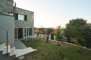 A modern stone building with a patio, outdoor seating, and a small garden. - Luxury Apartment is an exclusive residence located in the upper part of Portovenere, designed for guests seeking elegance, comfort, and relaxation. The refined interiors, enhanced by underfloor heating and air conditioning throughout the property, create (Porto Venere)