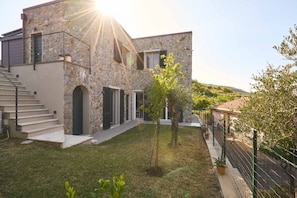 A stone building with a staircase, a small tree, and a fence. - Luxury Apartment is an exclusive residence located in the upper part of Portovenere, designed for guests seeking elegance, comfort, and relaxation. The refined interiors, enhanced by underfloor heating and air conditioning throughout the property, create (Porto Venere)