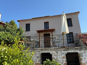 A two-story building with a balcony, a pergola, and a white umbrella. - Tsagarakis Guesthouse & Pool Room.2 with Mountain & Pool View, Wi-Fi, and Air Conditioning (Xinovrysi)