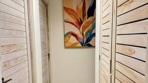 Um corredor com paredes revestidas de madeira, piso de madeira e um quadro abstrato colorido na parede.