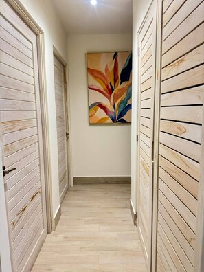 A hallway with wooden panel walls, a wooden floor, and a colorful abstract painting on the wall. - Apartamento frente al mar con vista a la piscina (punta chame)