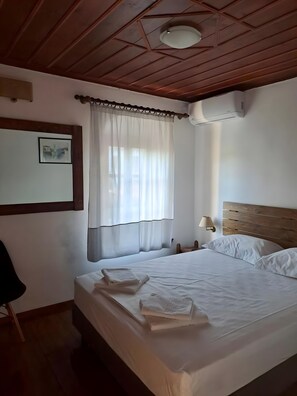 A bedroom with a wooden ceiling, a bed with white linens, a bedside lamp, and a picture on the wall. - Tsagarakis Guesthouse & Pool Room .4 with Mountain & Pool View, Wi-Fi, Air Conditioning (Xinovrysi)