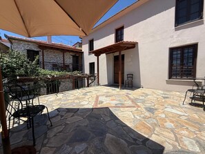 A courtyard with stone flooring, outdoor furniture, and a pergola. - Tsagarakis Guesthouse & Pool Room .4 with Mountain & Pool View, Wi-Fi, Air Conditioning (Xinovrysi)