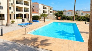 Ein Pool mit Liegestühlen, Palmen und mehrstöckigen Gebäuden.