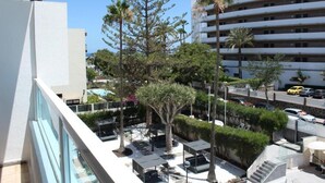 A hotel courtyard with outdoor seating, palm trees, and a multi-story building in the background. - Apartamentos Fayna (Gran Canarias)