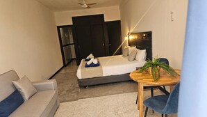A hotel room with a bed, a sofa, a round wooden table, and a ceiling fan. - Apartamentos Fayna (Gran Canarias)