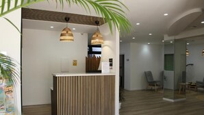 A reception desk with a vertical wooden panel design, two hanging pendant lights, and a glass partition wall. - Apartamentos Fayna (Gran Canarias)