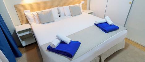 Ein Hotelzimmer mit einem Bett, zwei Nachttischen, einem Holzkopfteil und einer Wandleuchte.