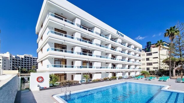 A modern hotel with a pool, multiple balconies, and a clear blue sky. - Apartamentos Fayna (Gran Canarias)