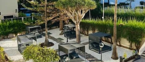 An outdoor patio area with seating, trees, and a building in the background.