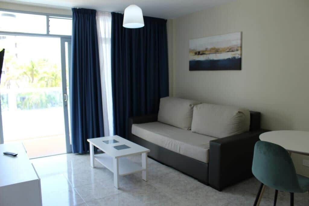 A modern living room with a sofa, a small table, a chair, and a painting on the wall.