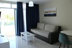Ein modernes Wohnzimmer mit einer Couch, einem kleinen Tisch, einem Sessel und einem Bild an der Wand.