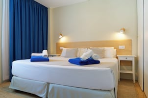 Una camera d'albergo con un letto grande, due comodini, una testiera in legno e una tenda blu.
