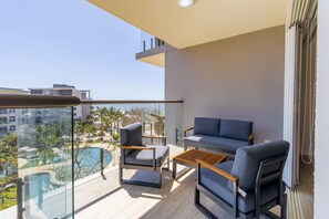 Ein Balkon mit einer Couch, zwei Sesseln und einem kleinen Tisch.