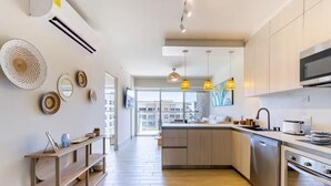 Uma cozinha moderna com ilha central, eletrodomésticos embutidos e iluminação pendente.