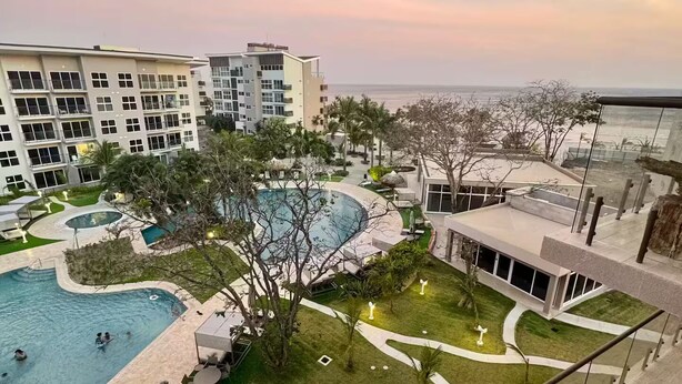 Um resort com piscina, jardim paisagístico e vista para o oceano.