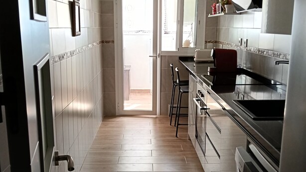 Una cocina moderna con piso de madera, electrodomésticos de acero inoxidable y vistas al exterior.