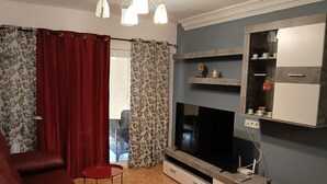Una sala de estar con un sofá, un televisor, una mesita y una chimenea.